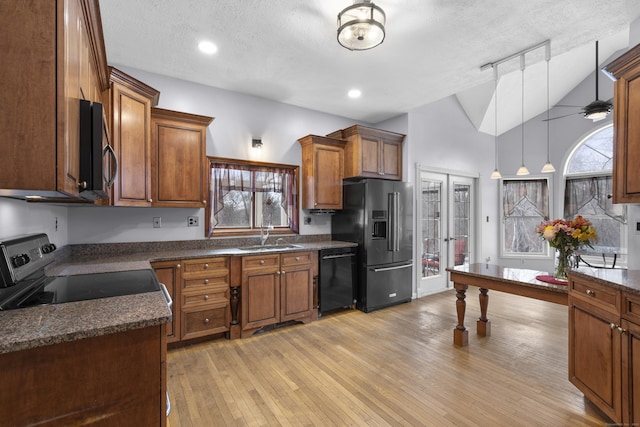 kitchen with vaulted ceiling, light wood-type flooring, pendant lighting, ceiling fan, and black appliances