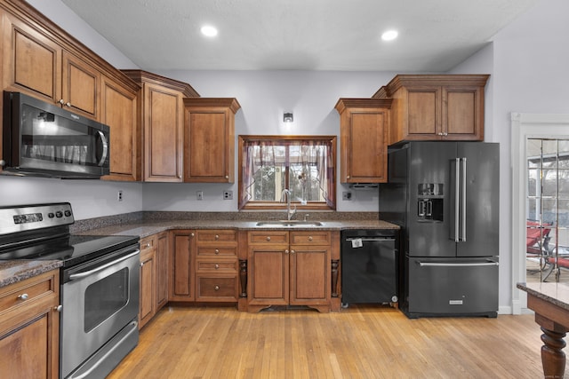 kitchen featuring plenty of natural light, sink, light hardwood / wood-style floors, and black appliances