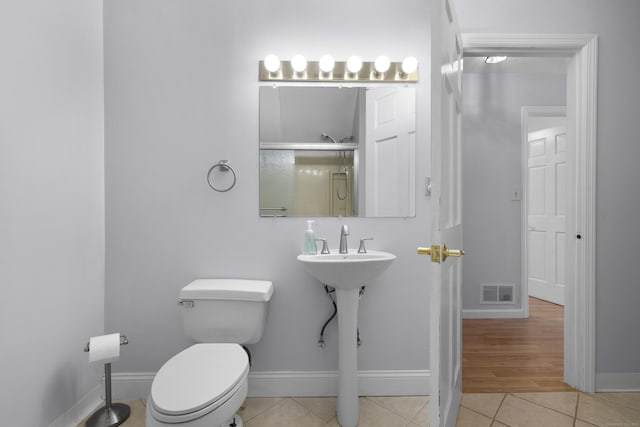 bathroom featuring tile patterned flooring, an enclosed shower, and toilet