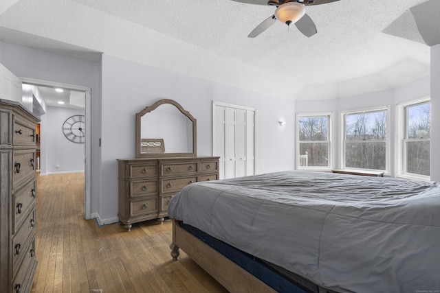 bedroom with a closet, ceiling fan, hardwood / wood-style floors, and a textured ceiling