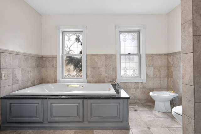 bathroom featuring a bidet, a bathing tub, a wealth of natural light, and toilet