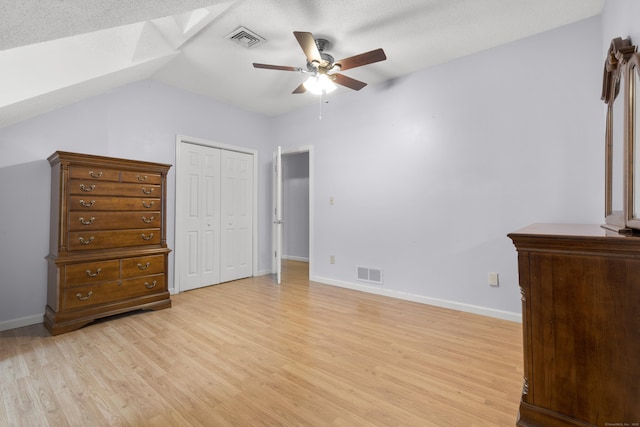 unfurnished bedroom featuring ceiling fan, vaulted ceiling, light wood-type flooring, and a closet