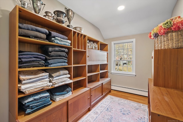 spacious closet with light hardwood / wood-style flooring, lofted ceiling, and a baseboard heating unit