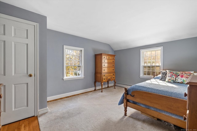 bedroom with a baseboard radiator, lofted ceiling, multiple windows, and light hardwood / wood-style flooring