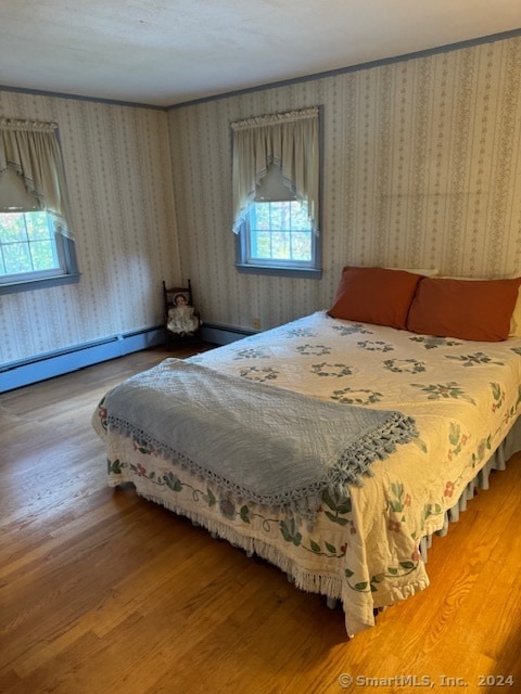 bedroom featuring a baseboard radiator and hardwood / wood-style flooring