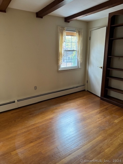 spare room with light hardwood / wood-style floors, beamed ceiling, and a baseboard radiator