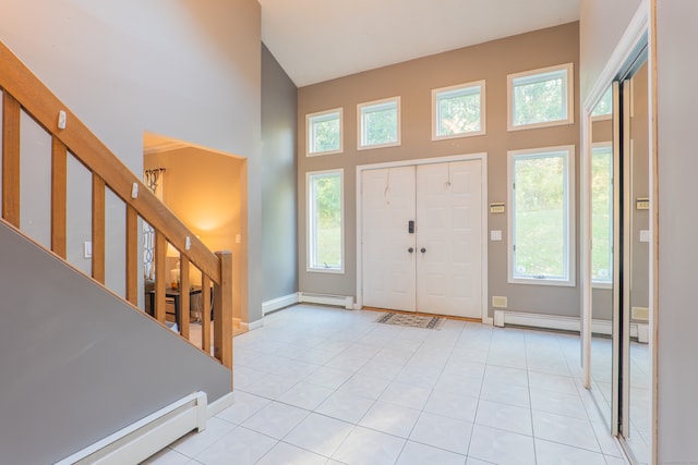 tiled entrance foyer featuring a towering ceiling, a healthy amount of sunlight, and baseboard heating