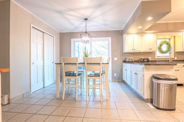 kitchen with hanging light fixtures, ornamental molding, light tile patterned floors, and white cabinets