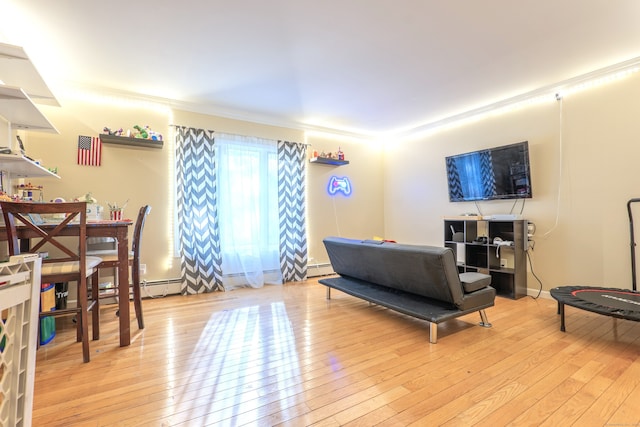 living room with light hardwood / wood-style floors, ornamental molding, and a baseboard heating unit