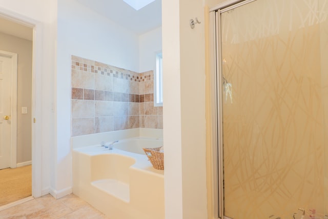 bathroom featuring a skylight, tile patterned floors, and separate shower and tub