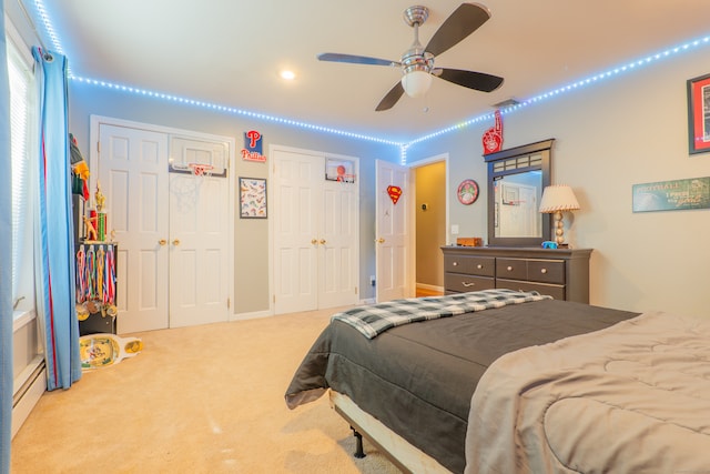 bedroom featuring light carpet, multiple closets, and ceiling fan