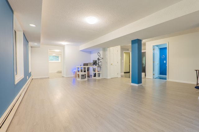 workout area featuring a textured ceiling, a baseboard radiator, and light wood-type flooring