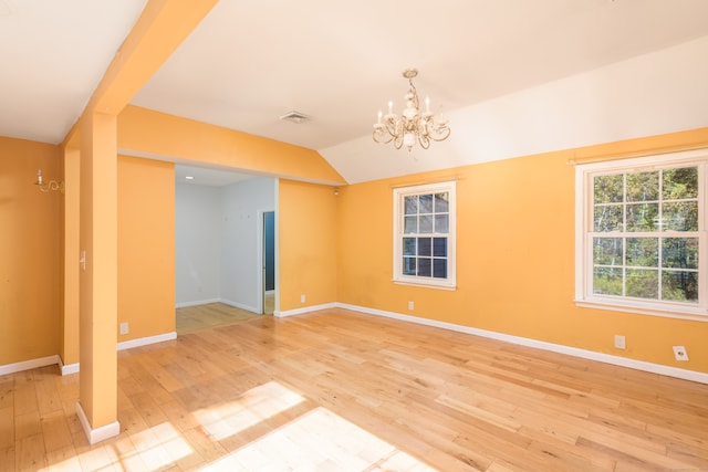 spare room with lofted ceiling, an inviting chandelier, and hardwood / wood-style flooring