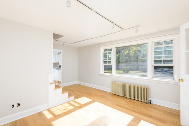 spare room featuring radiator heating unit and hardwood / wood-style flooring