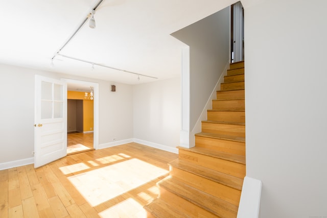 staircase featuring wood-type flooring and track lighting