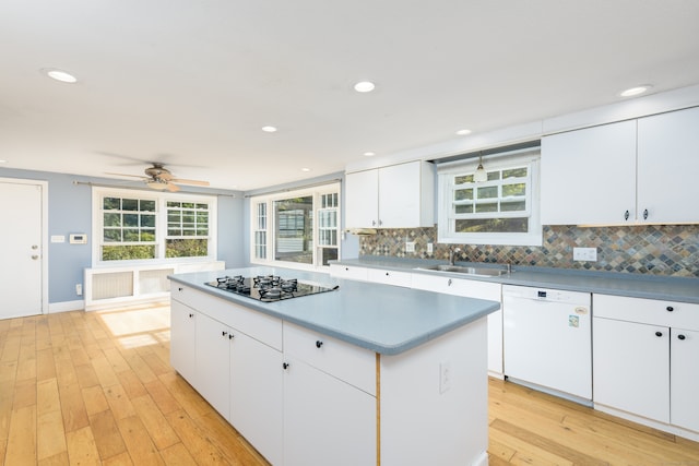 kitchen featuring light wood-type flooring, black gas cooktop, white cabinets, sink, and white dishwasher