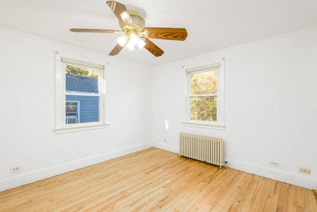 unfurnished room with ceiling fan, radiator, and light hardwood / wood-style floors