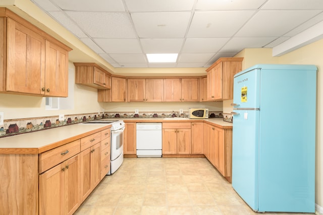 kitchen with light brown cabinets, a paneled ceiling, sink, and white appliances