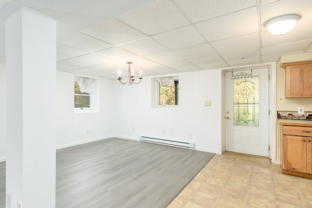 unfurnished dining area featuring light hardwood / wood-style flooring, plenty of natural light, a drop ceiling, and a baseboard heating unit