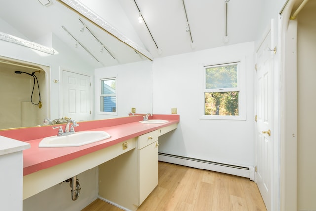 bathroom with hardwood / wood-style floors, vaulted ceiling, vanity, and a baseboard radiator