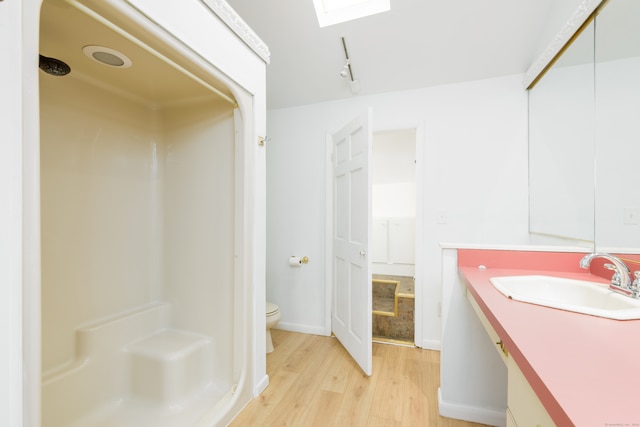 bathroom featuring vanity, a shower, hardwood / wood-style floors, and toilet