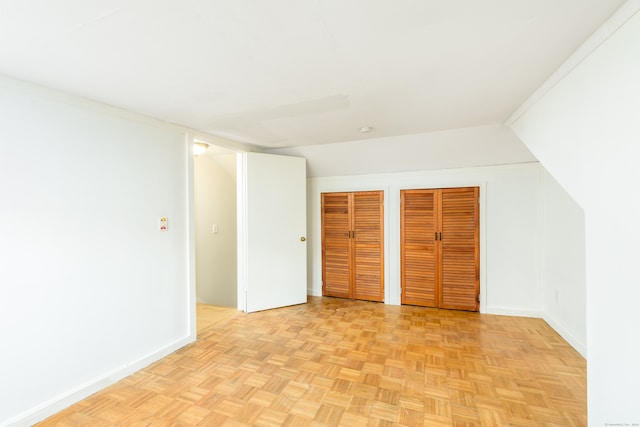 unfurnished bedroom with light parquet floors and multiple closets