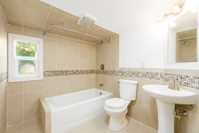 bathroom featuring toilet, tile patterned flooring, tile walls, and tiled shower / bath combo