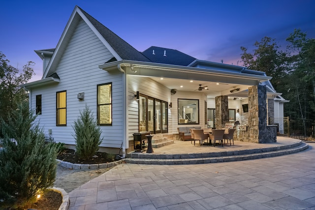 back house at dusk featuring a patio area and ceiling fan