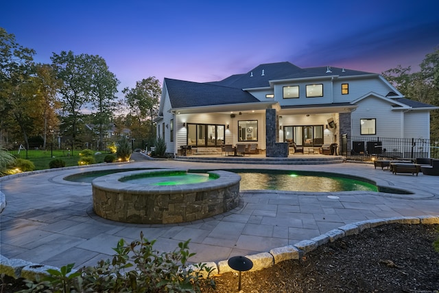 back house at dusk with a patio and a swimming pool with hot tub