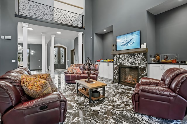 living room with a towering ceiling, ornate columns, french doors, and a premium fireplace