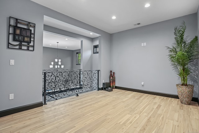 empty room with a notable chandelier and light hardwood / wood-style flooring