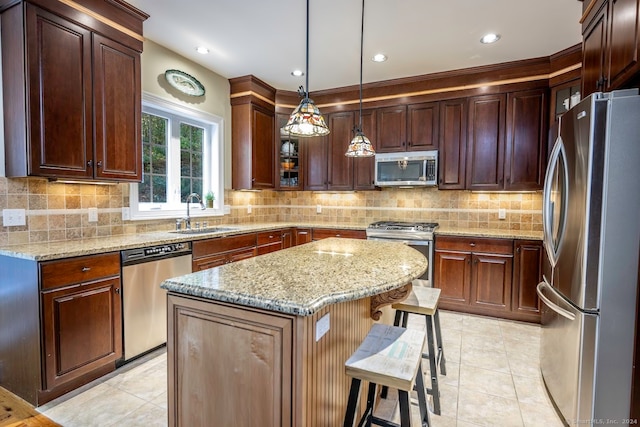 kitchen with sink, decorative light fixtures, a center island, appliances with stainless steel finishes, and a breakfast bar