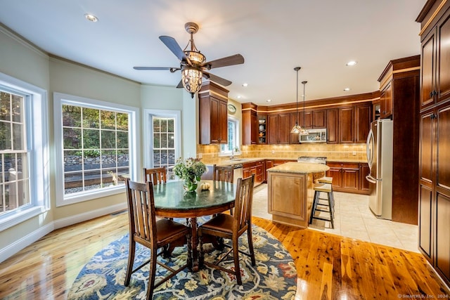 dining area with ceiling fan, light hardwood / wood-style flooring, crown molding, and sink