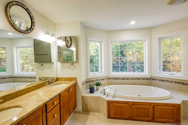 bathroom with tile patterned flooring, tiled tub, and vanity