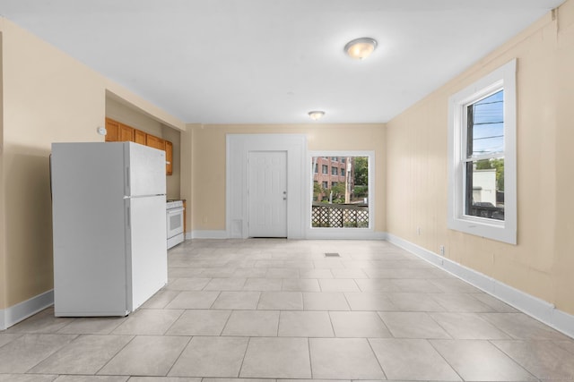 kitchen featuring light tile patterned flooring and white appliances