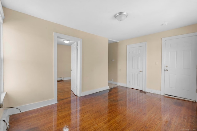 unfurnished bedroom with wood-type flooring and baseboard heating