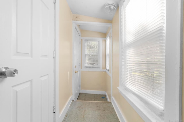 corridor featuring plenty of natural light and vaulted ceiling