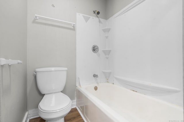 bathroom with shower / bathing tub combination, hardwood / wood-style floors, and toilet