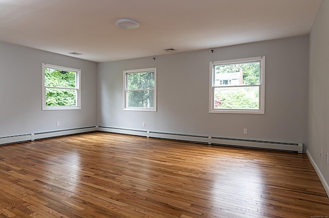 spare room with a baseboard heating unit and hardwood / wood-style floors