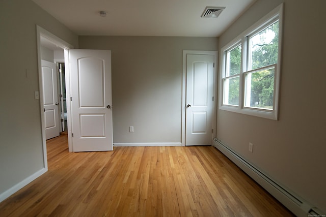 unfurnished bedroom featuring a baseboard radiator and light hardwood / wood-style flooring