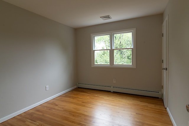 empty room with light hardwood / wood-style flooring and baseboard heating