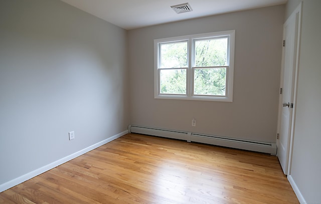 unfurnished room with a baseboard heating unit and light hardwood / wood-style flooring