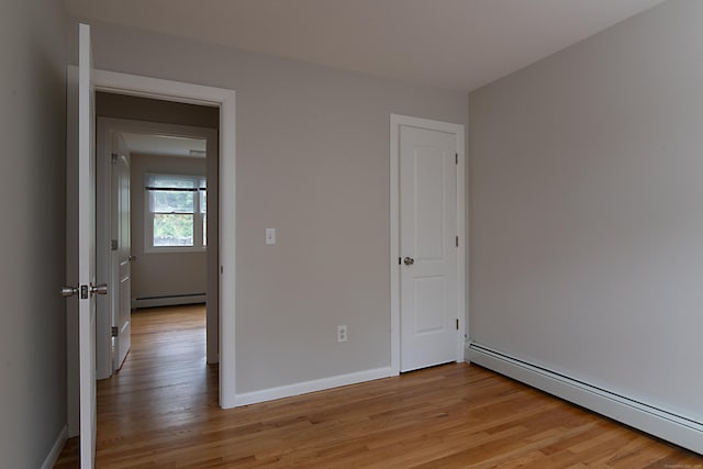 interior space featuring a baseboard heating unit and light hardwood / wood-style floors