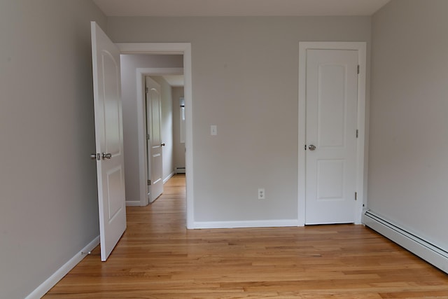 unfurnished bedroom featuring a baseboard radiator and light hardwood / wood-style flooring