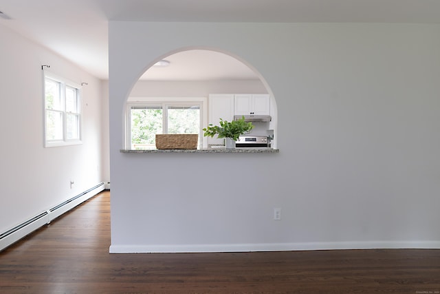 spare room featuring dark wood-type flooring and baseboard heating