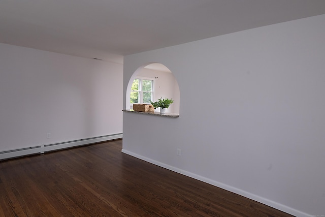 unfurnished room with baseboard heating and dark hardwood / wood-style floors