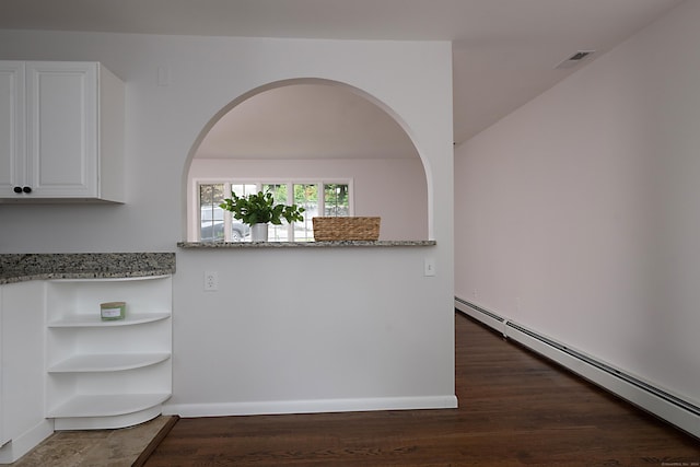 kitchen with white cabinetry, light stone counters, and baseboard heating