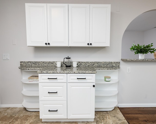 interior space featuring light stone countertops and white cabinets