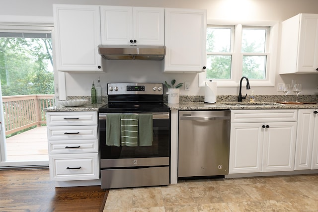 kitchen featuring light stone counters, a healthy amount of sunlight, stainless steel appliances, and white cabinets