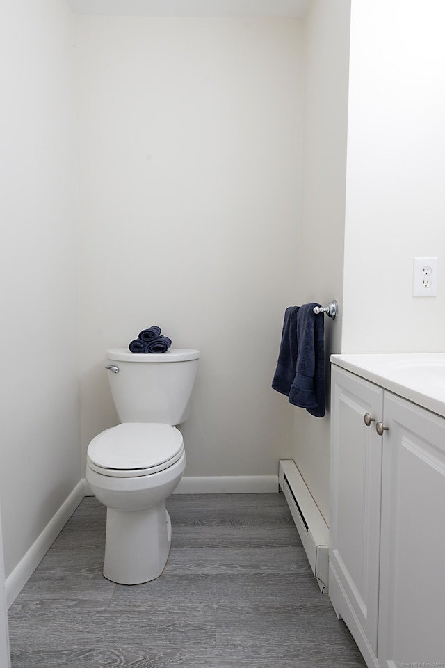 bathroom featuring vanity, a baseboard heating unit, hardwood / wood-style flooring, and toilet